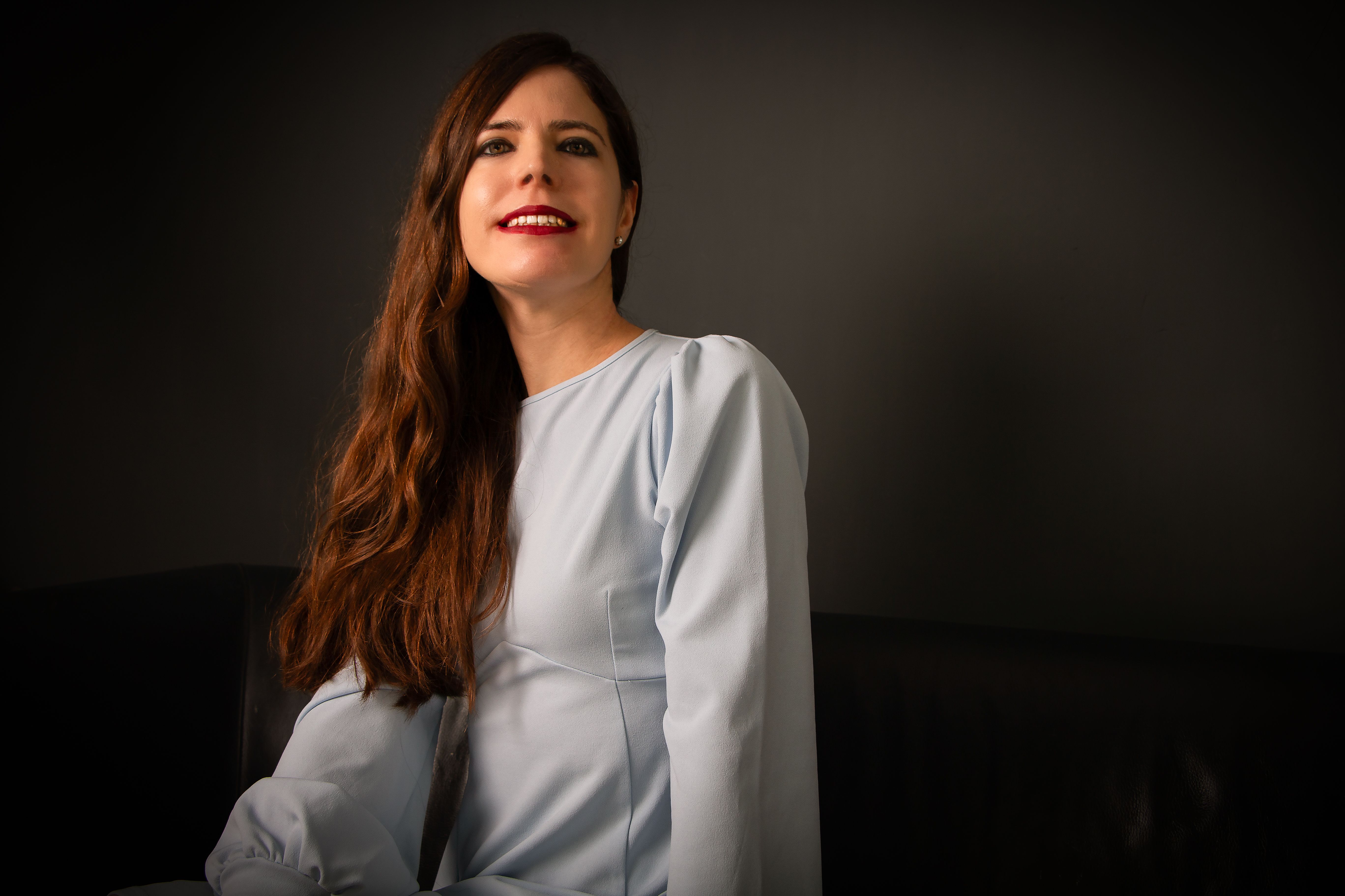 A sophisticated portrait of a woman in a light blue dress exuding elegance and charm. Ideal for fashion and lifestyle themes.