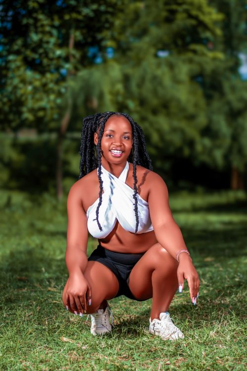 Free Vibrant portrait of a woman in active wear, smiling outdoors in a lush garden. Stock Photo