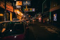 夜晚，香港街头霓虹灯色彩缤纷，出租车停靠一旁，景象明亮