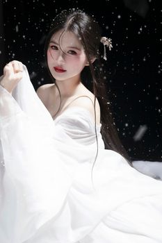 Elegant woman in white dress with snow accents, capturing a serene winter moment.