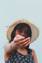一位时尚的年轻女子在户外将草帽伸向相机