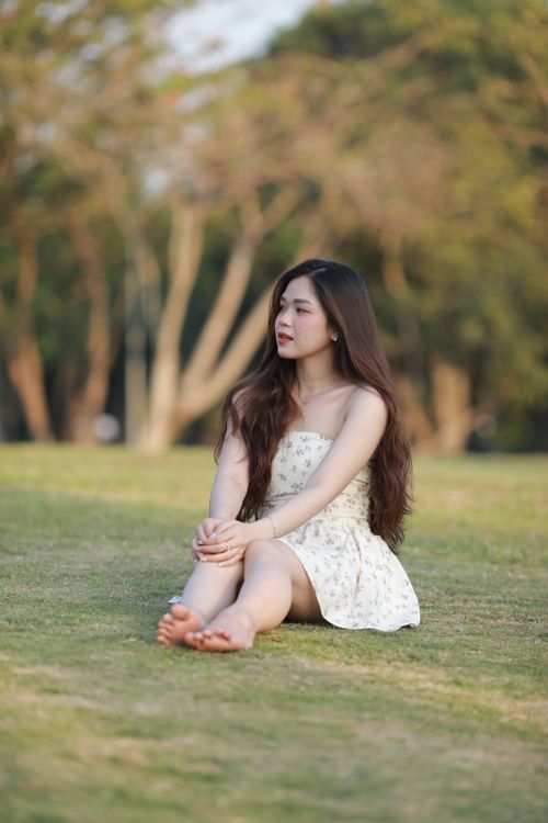 Free A woman enjoys a tranquil moment sitting on grass in a sunny park. Stock Photo