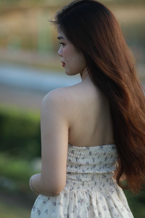 Free A woman in a sundress enjoys a peaceful moment outdoors. Stock Photo