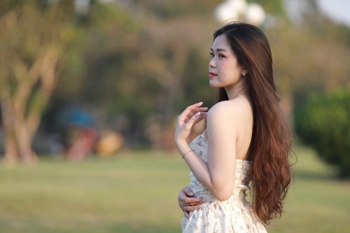 Free A serene outdoor portrait of a young woman in a floral dress with long flowing hair. Stock Photo