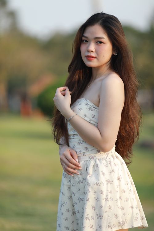 Free Portrait of a young woman in a floral dress enjoying a sunny day outdoors. Stock Photo