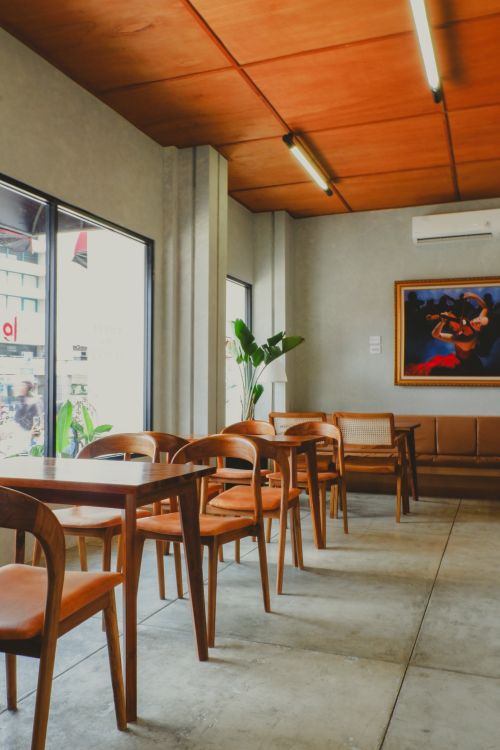 Free Cozy modern cafe interior with wooden tables and chairs in natural light. Stock Photo