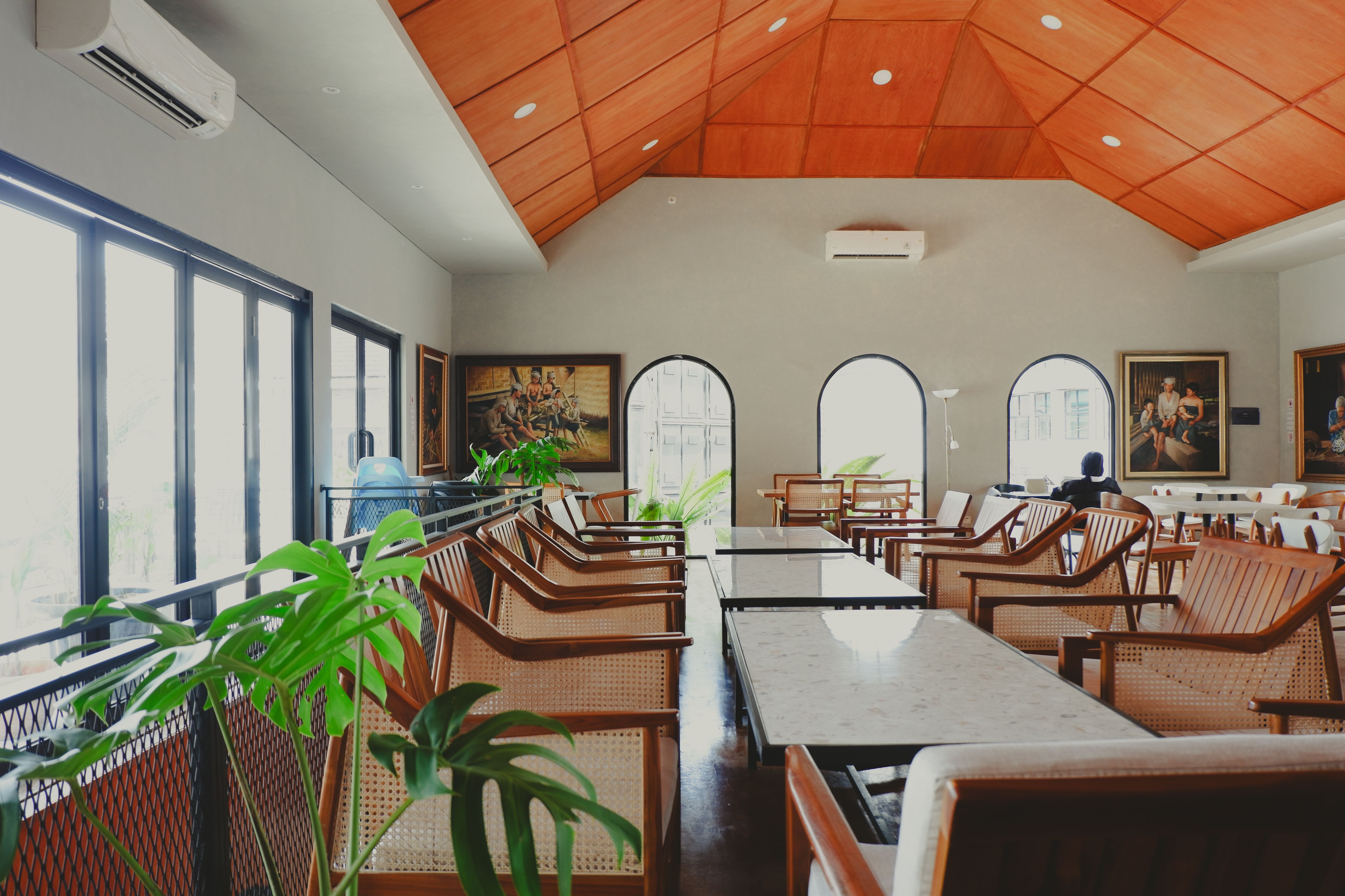 A stylish cafe interior featuring wooden furniture and artistic decor in a bright and airy atmosphere.