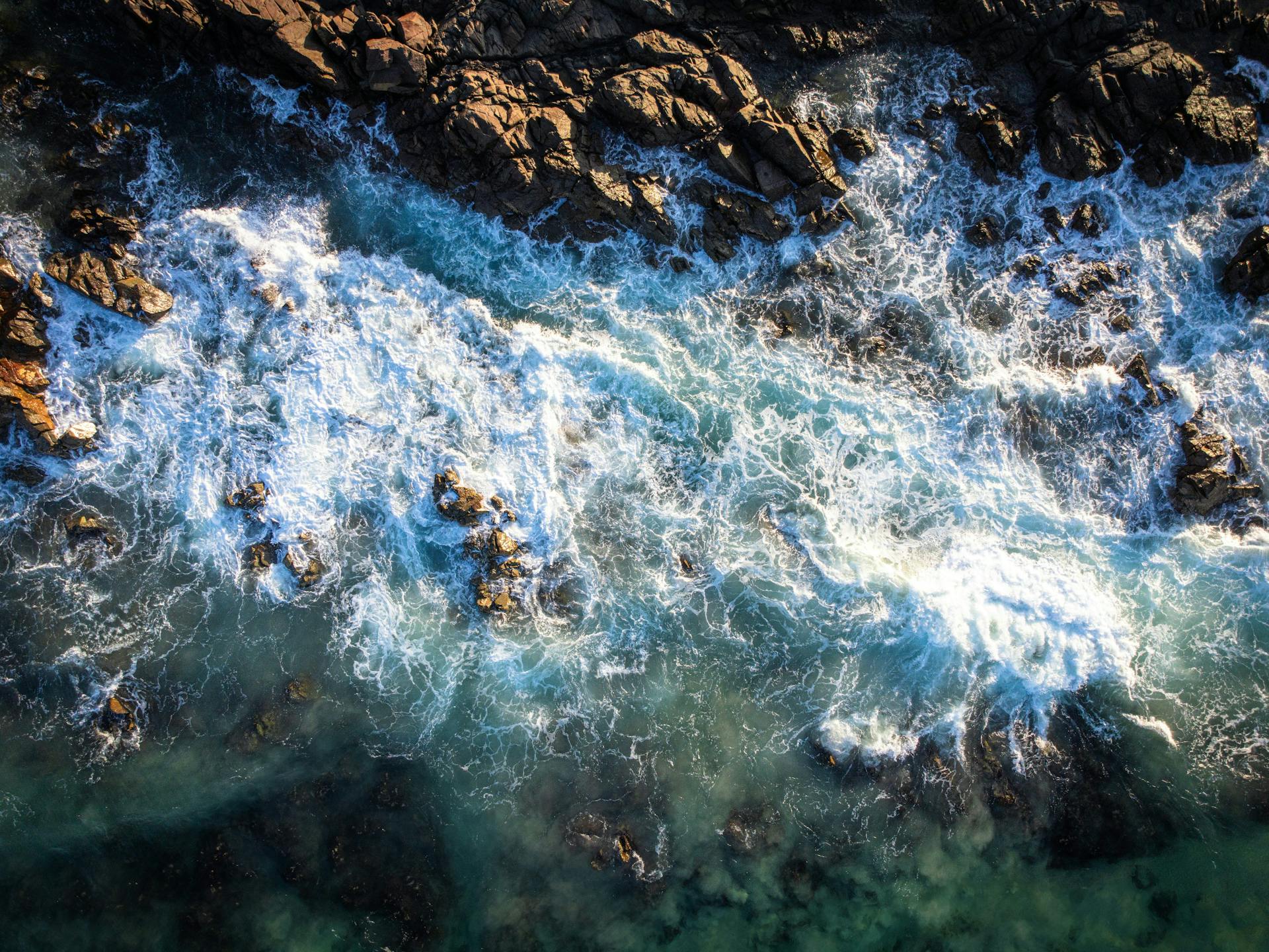 Dramatic aerial shot of waves crashing against rocks at Hastings Point, NSW, Australia, showcasing natural beauty.