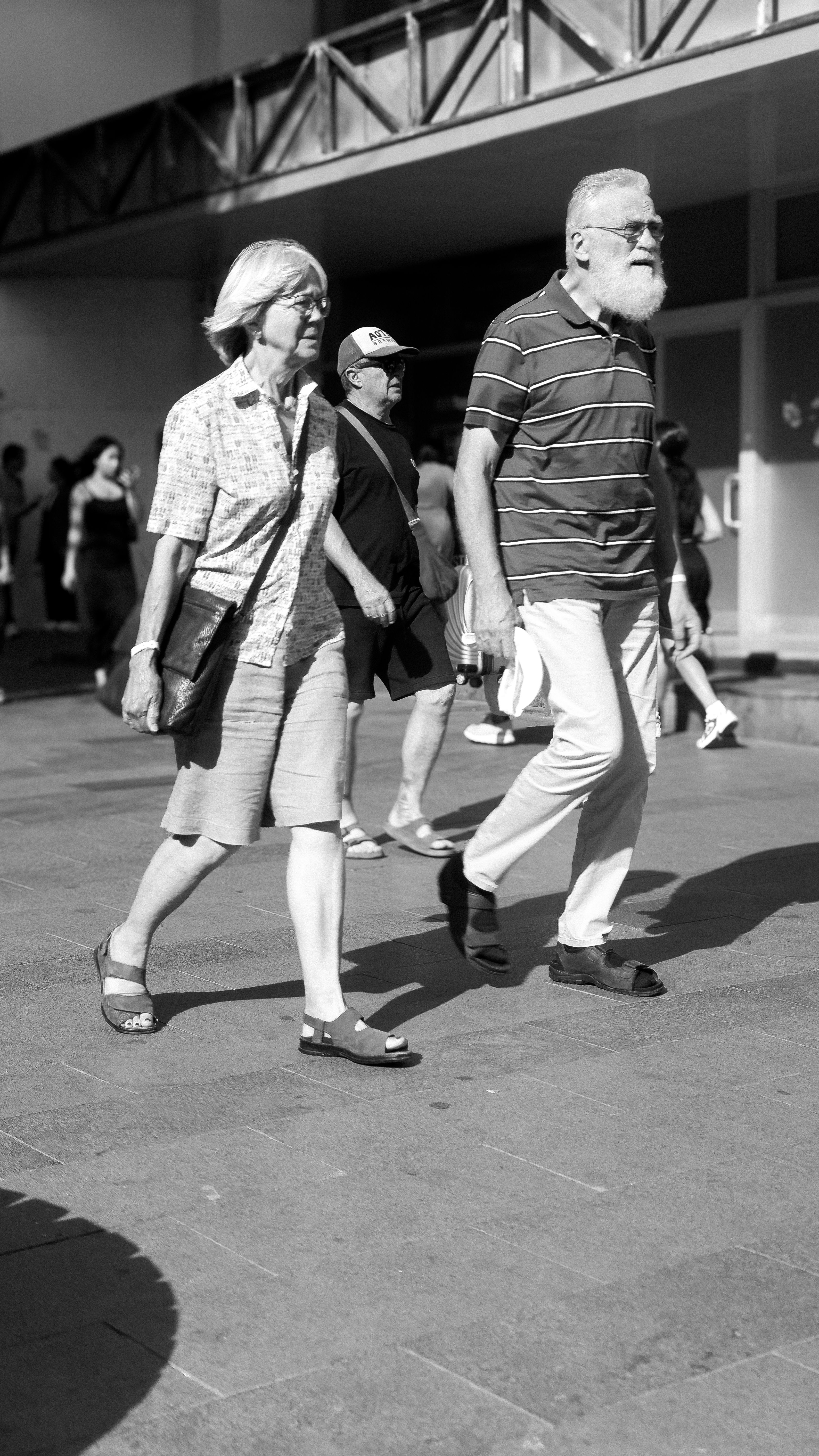 Black and white photo of an elderly couple walking confidently in an urban setting.