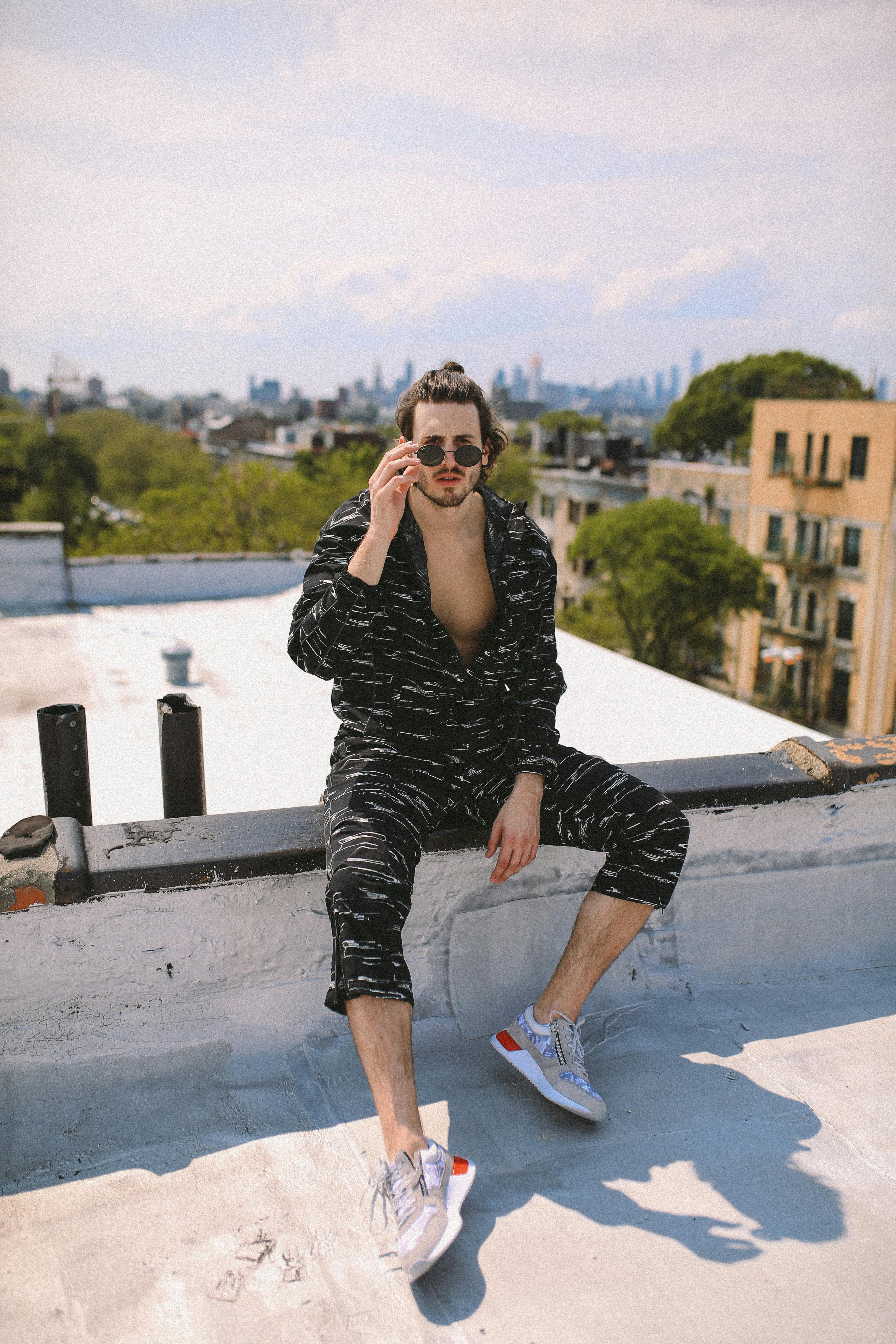 Man in stylish sportswear on a NY rooftop, embodying urban fashion with city views.