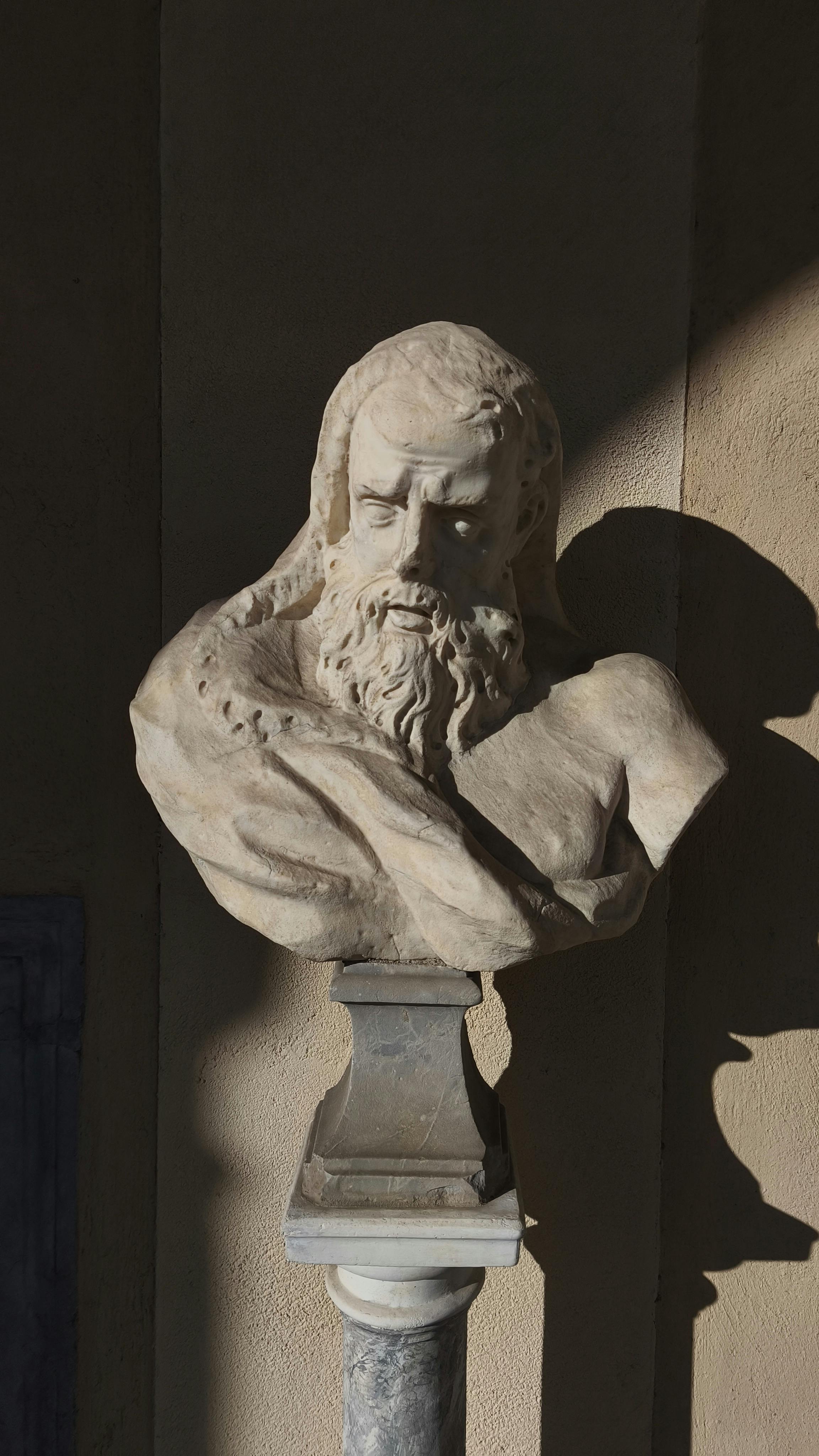 Stone Roman bust sculpture in shadowy sunlight, captured in Genoa, Italy.