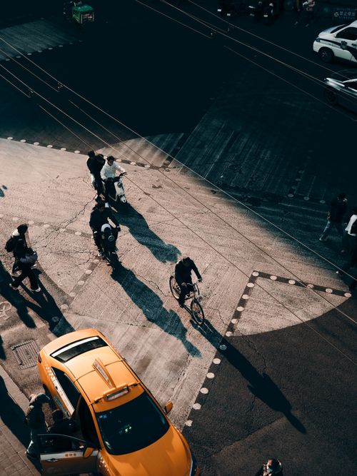 Free Aerial view of a busy urban crosswalk with cyclists and pedestrians under warm sunlight. Stock Photo