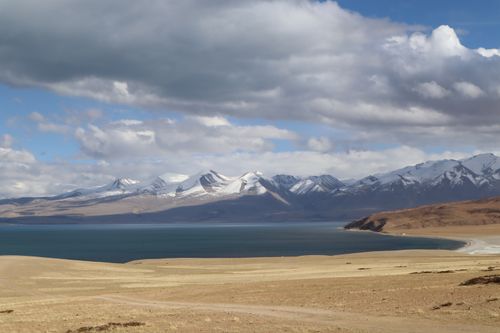 Free Serene landscape with snow-capped mountains and a clear lake under a cloudy sky. Stock Photo