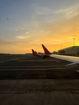 A breathtaking view of an airplane wing during sunrise at the airport.