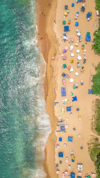 A vibrant aerial view of a beach with colorful umbrellas and gentle waves.