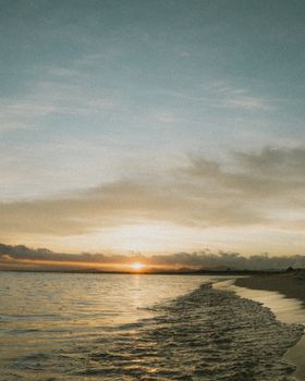 Beautiful sunset over a tranquil beach in Baja California, Mexico with soft waves and orange hues.