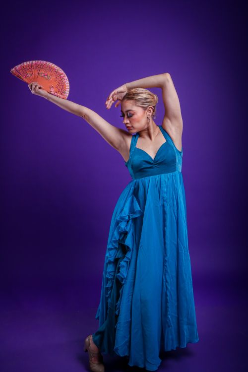 Free Graceful flamenco dancer posing with fan against a vivid purple background. Stock Photo