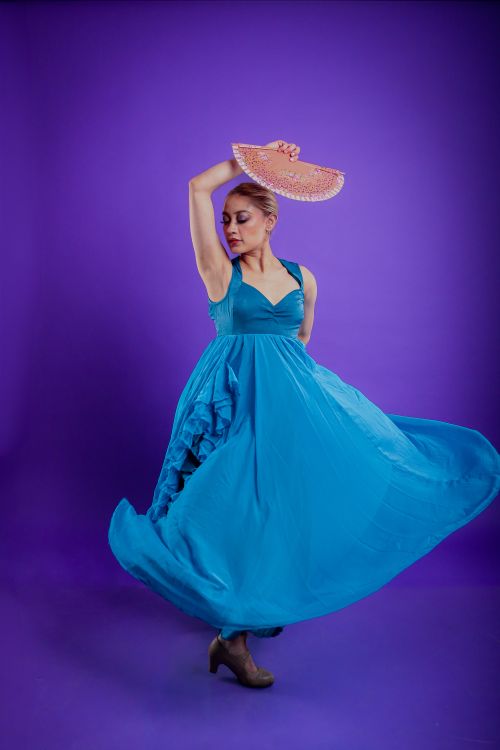 Free Graceful woman in blue dress dancing with a pink hat against a purple background. Stock Photo