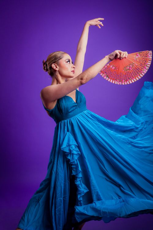Free A poised flamenco dancer showcases grace with an elegant fan against a vibrant purple background. Stock Photo