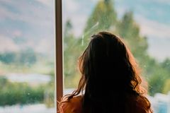 Silhouette of a woman looking out a window at a scenic mountain view in Cajamarca, Peru.