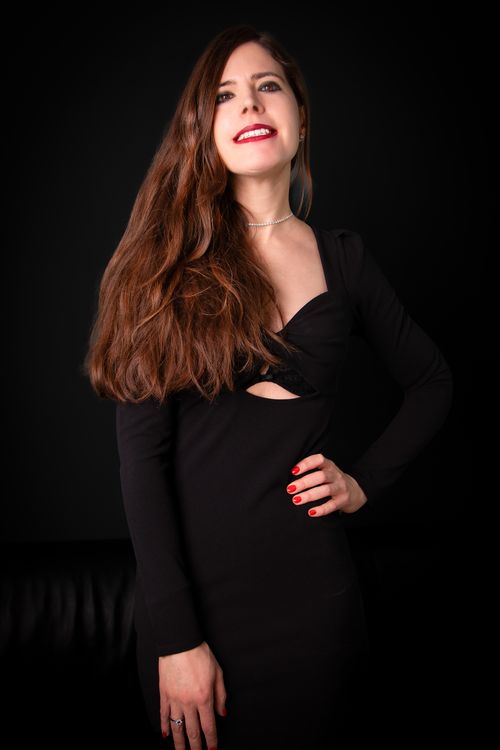 Free Beautiful woman posing confidently in a black dress against a black background. Stock Photo