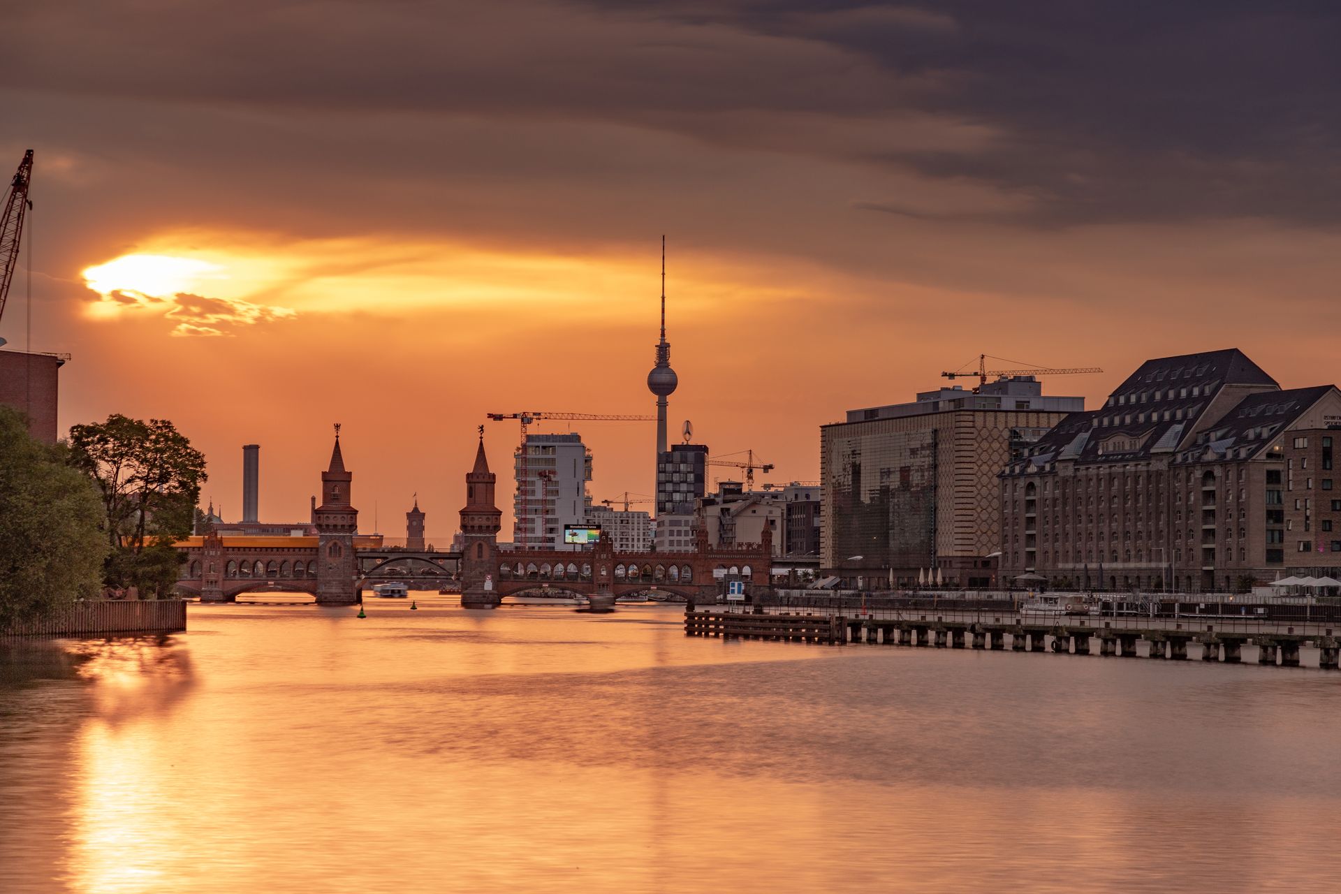 Dramatic sunset over Berlin's skyline featuring the iconic TV Tower and Oberbaum Bridge.