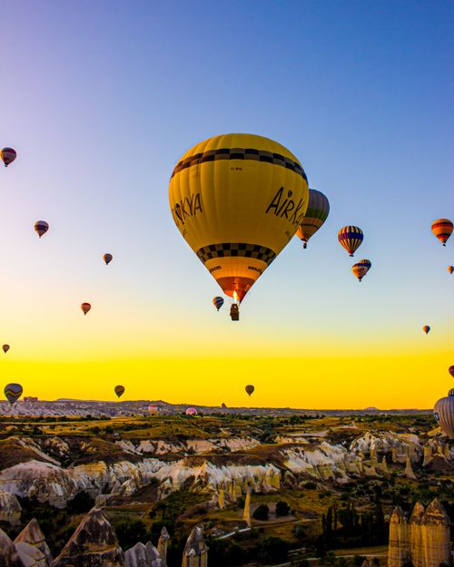 Free Captivating view of colorful hot air balloons over Cappadocia's unique landscape at sunrise. Stock Photo