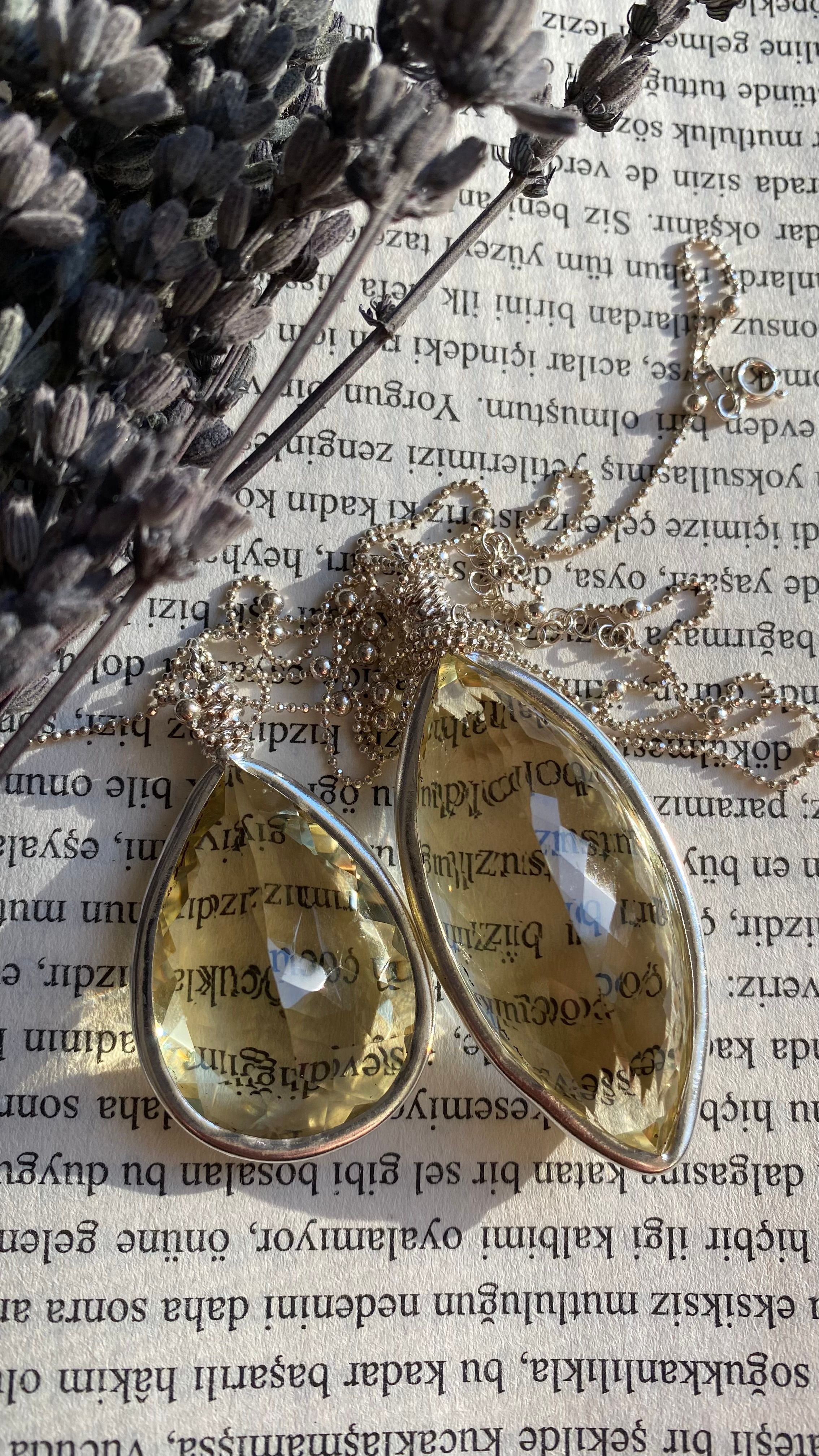 Elegant citrine gemstone necklaces with silver chains on vintage book pages backdrop.