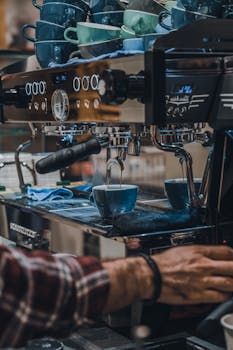 A barista operating a modern espresso machine to brew coffee in a cafe setting.