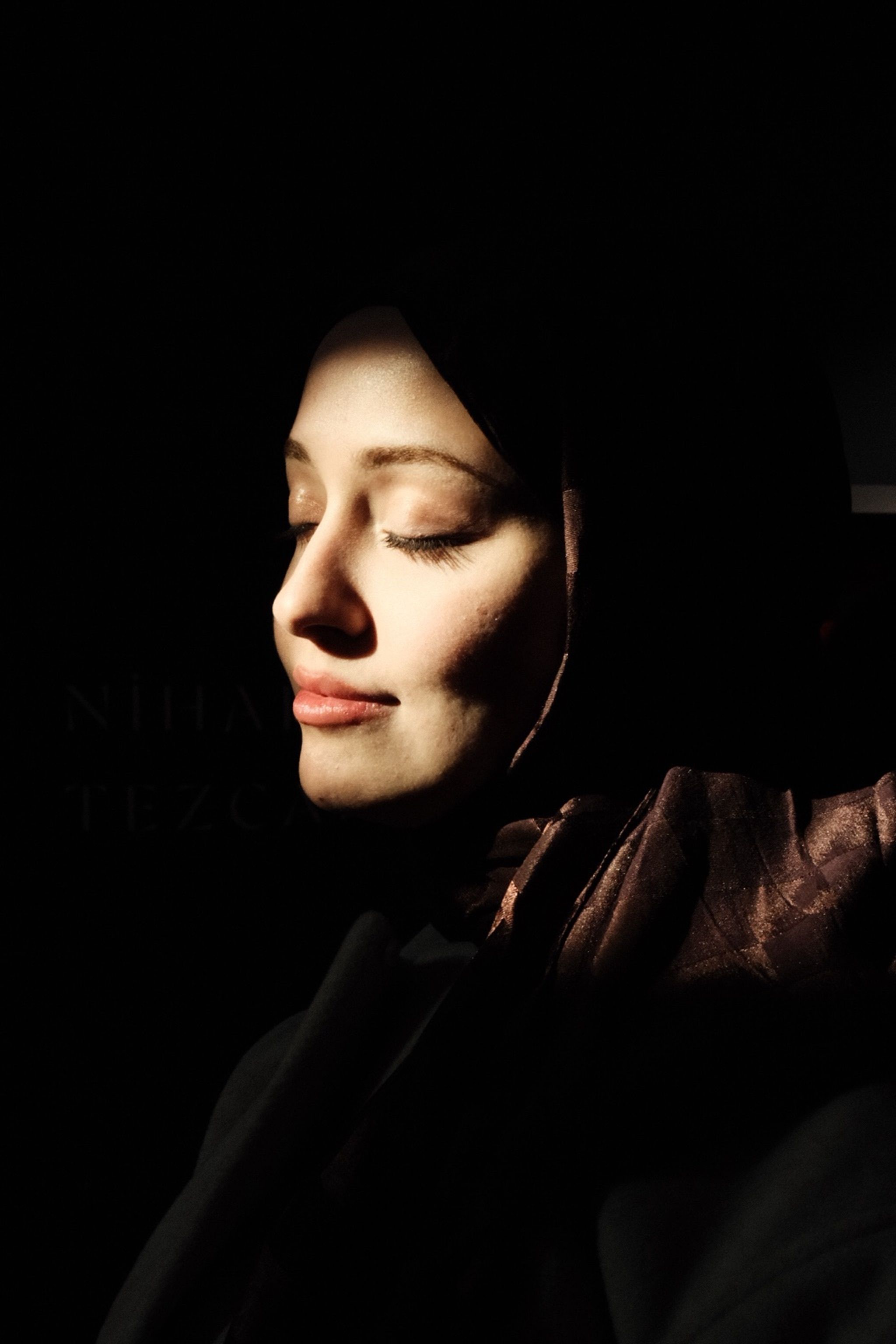 Close-up portrait of a serene woman in İstanbul, Türkiye, bathed in soft sunlight.