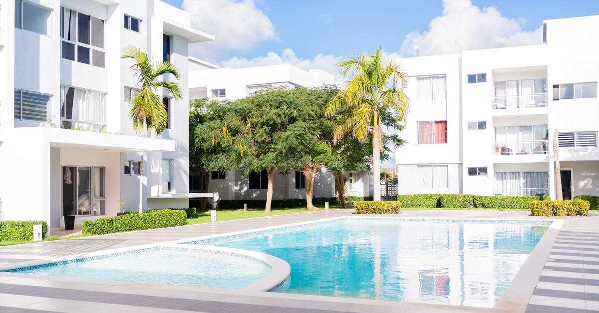 Bright modern apartment complex featuring an inviting outdoor pool area surrounded by lush greenery.