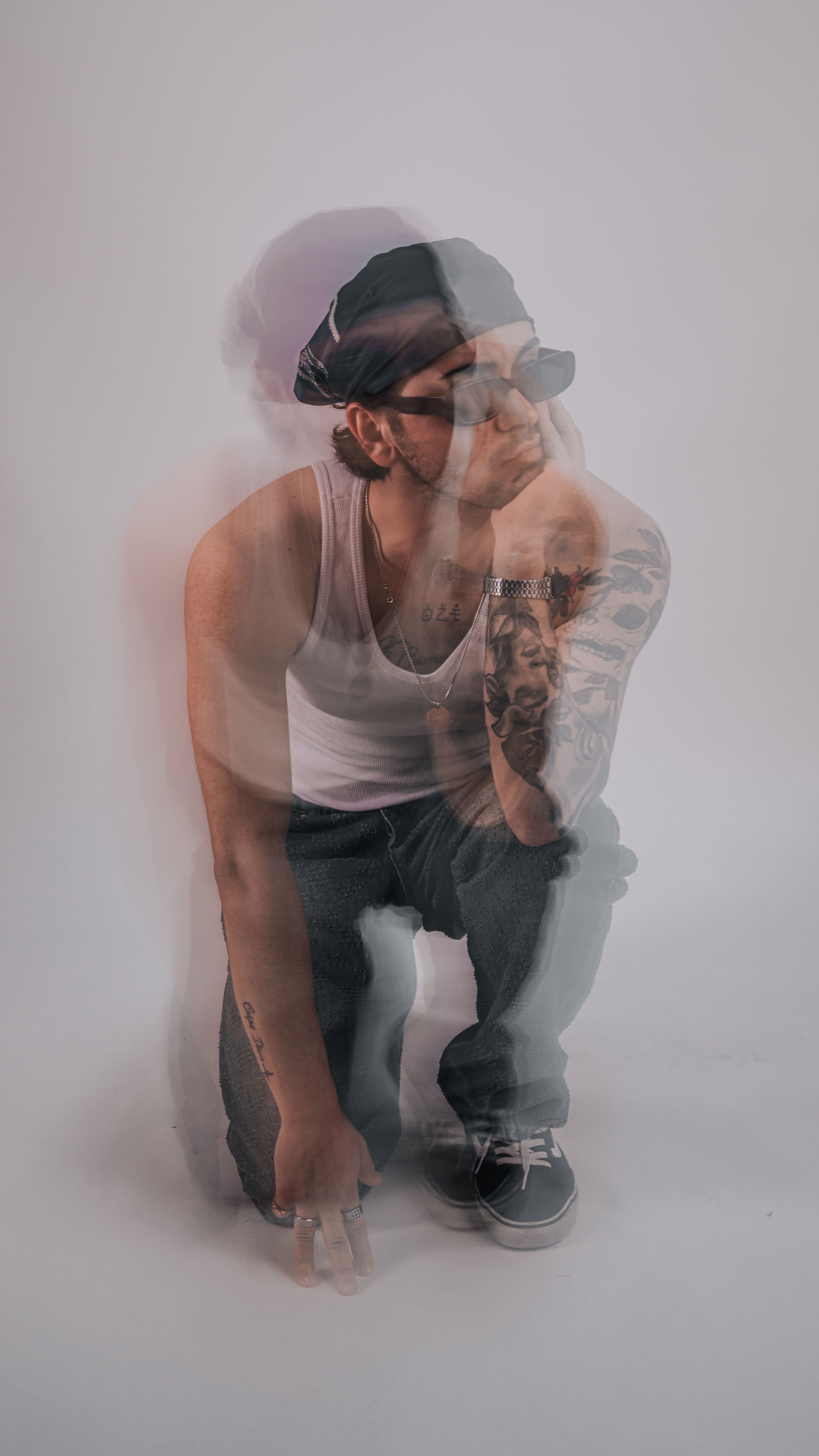 Artistic double exposure of a pensive man in casual attire against a plain background.