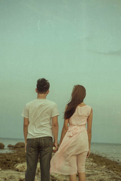 Back View Of A Young Man and Woman Facing The Sea