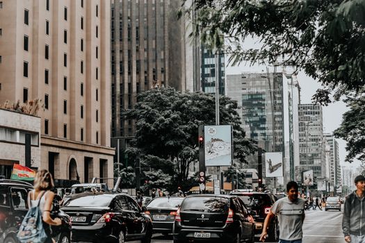 A crowded city street with vehicles, buildings, and people walking. Urban life captured outdoors.
