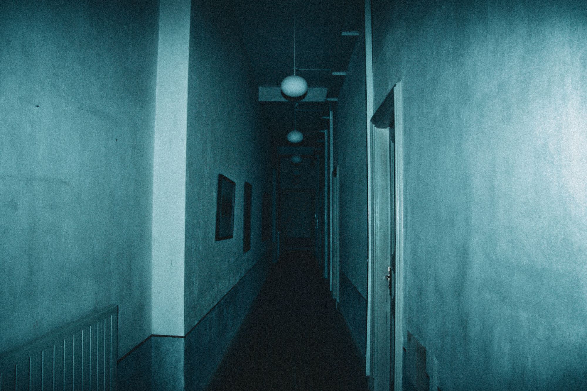 Pasillo oscuro de una casa iluminado apenas por la luz que se cuela por una puerta entreabierta