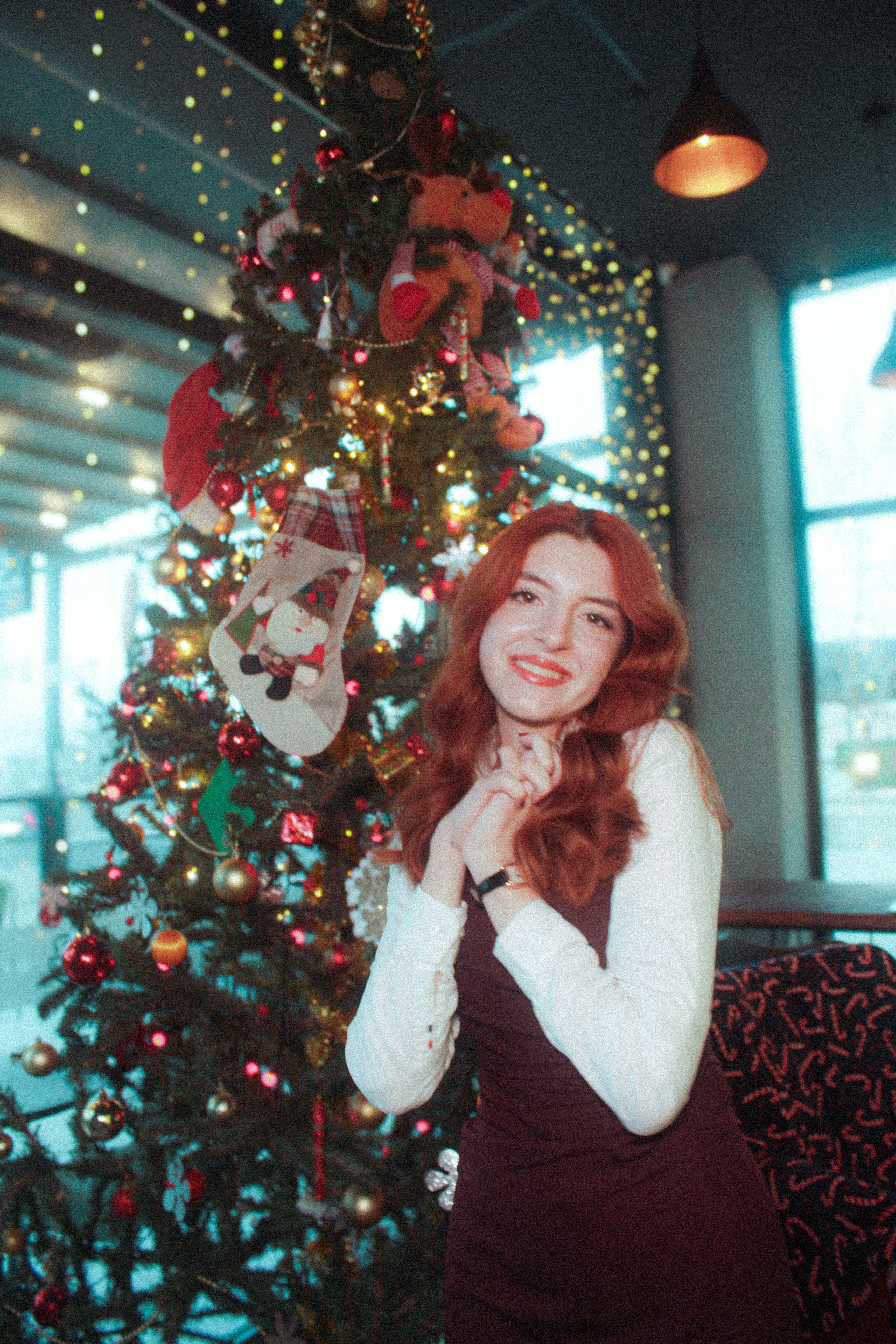 Woman enjoying festive holiday ambiance by a decorated Christmas tree.