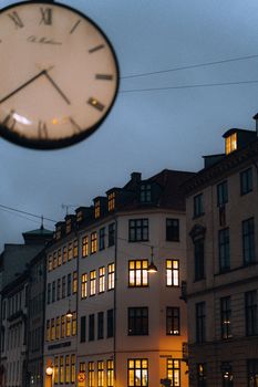 Moody evening view of Copenhagen street with warm lights and prominent clock.