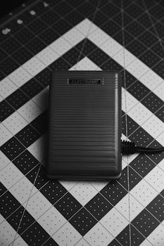 Monochrome close-up of a sewing machine foot pedal on a cutting board surface.