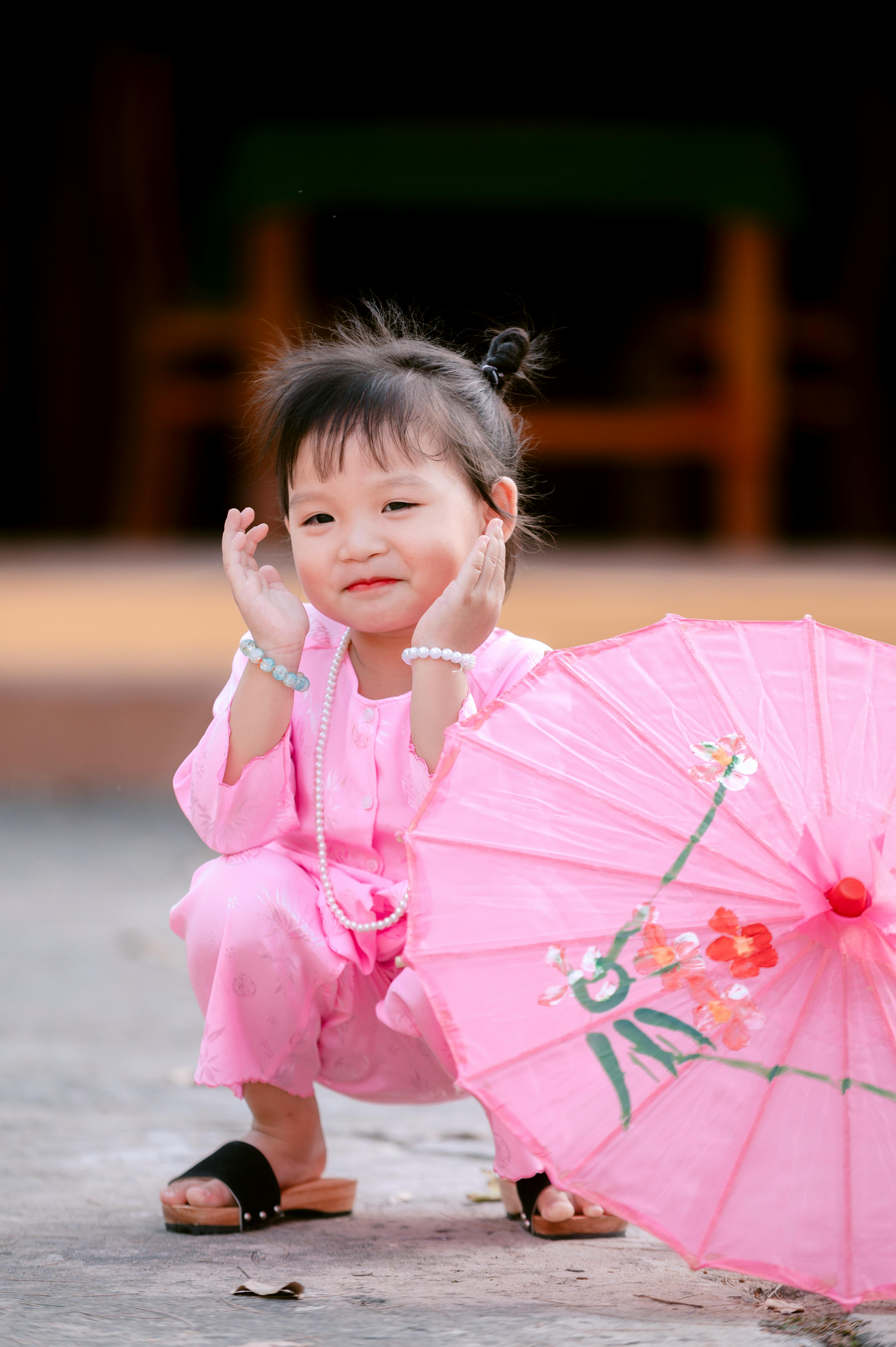 De franc Simpàtic nen amb un vestit tradicional rosa amb un para-sol rosa a l'aire lliure. Foto d'estoc