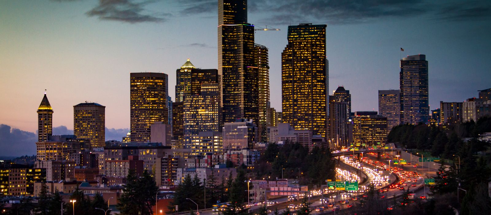 A stunning twilight view of Seattle's skyline with illuminated skyscrapers and busy traffic below. — flights from Kalispell to Seattle