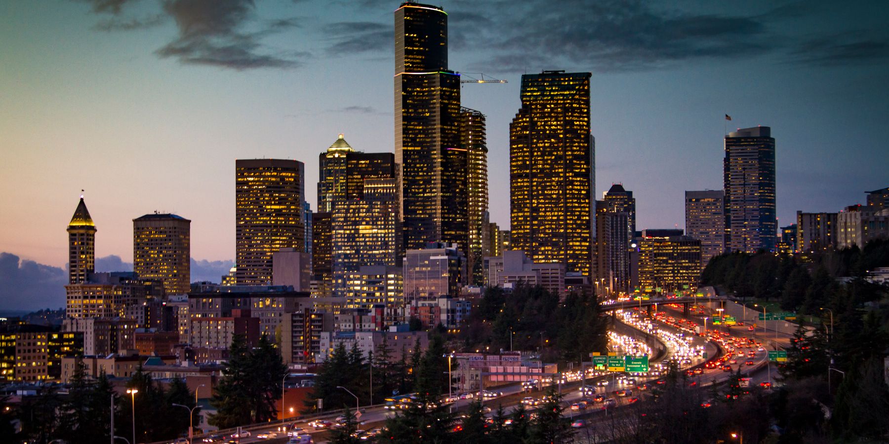 A stunning twilight view of Seattle's skyline with illuminated skyscrapers and busy traffic below.