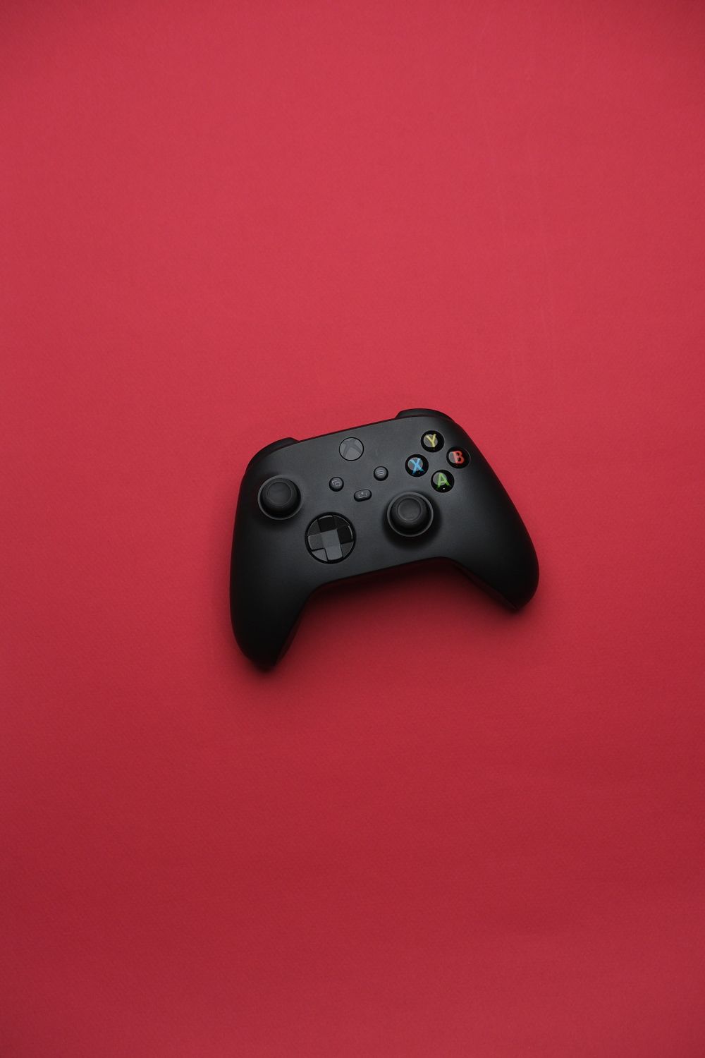 Black Gaming Controller on Vibrant Red Background · Free Stock Photo