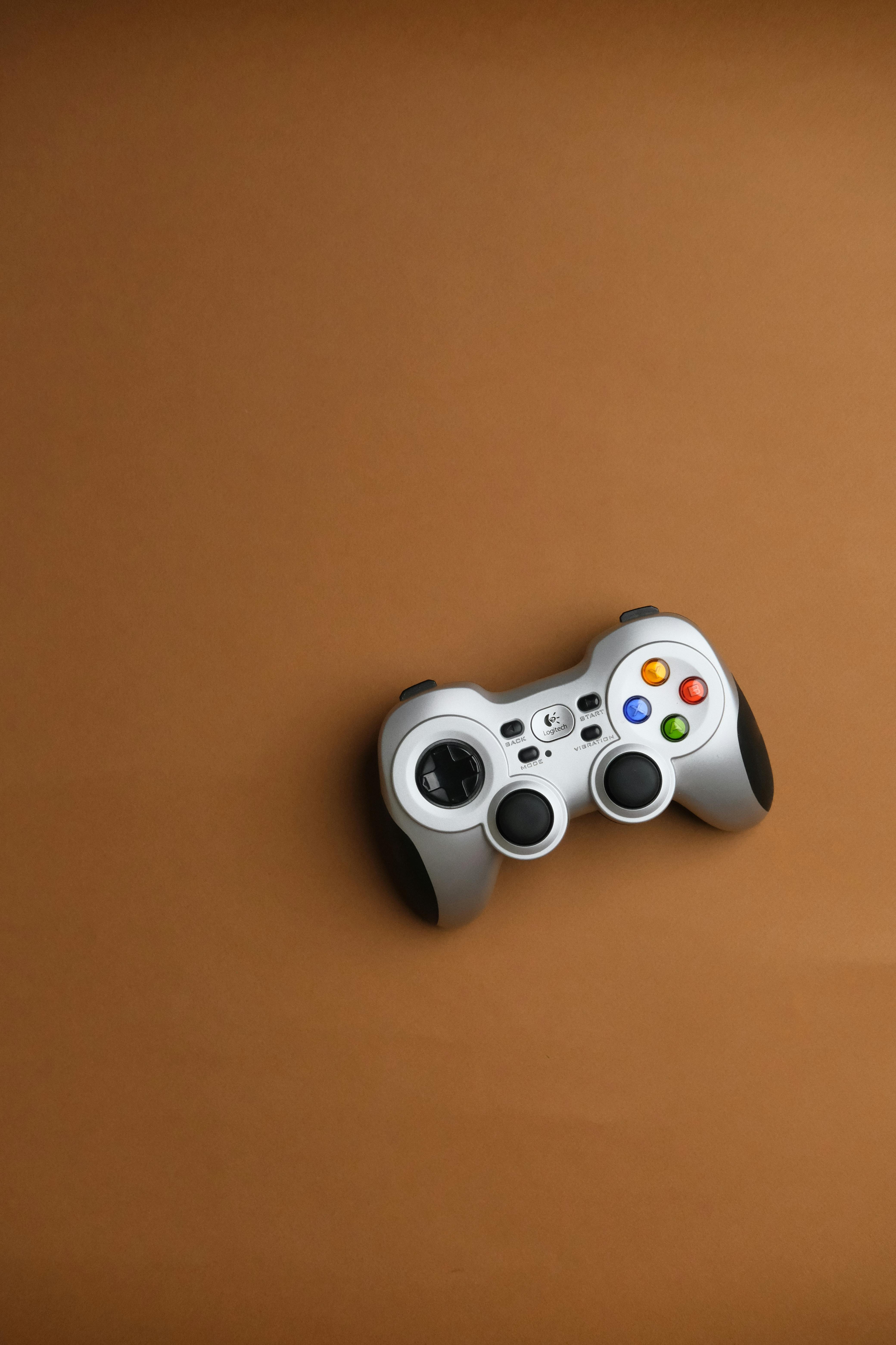 Wireless gaming controller on a brown background, showcasing digital entertainment and technology.