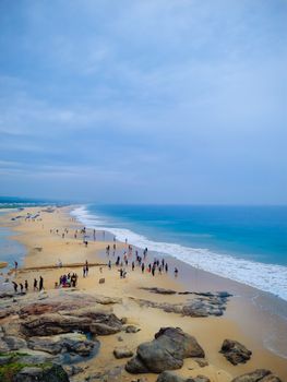 A vibrant view of a sandy beach with people enjoying a sunny day in Thiruvananthapuram, India.