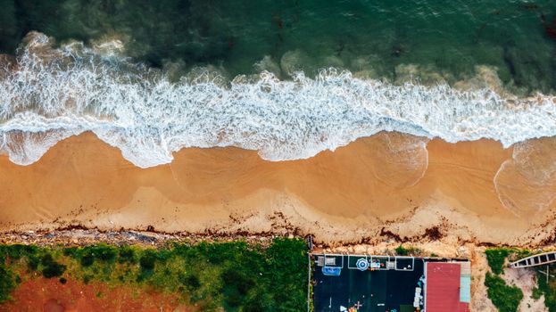 A mesmerizing aerial view showcasing waves crashing on a sandy beach, perfect for coastal themes.
