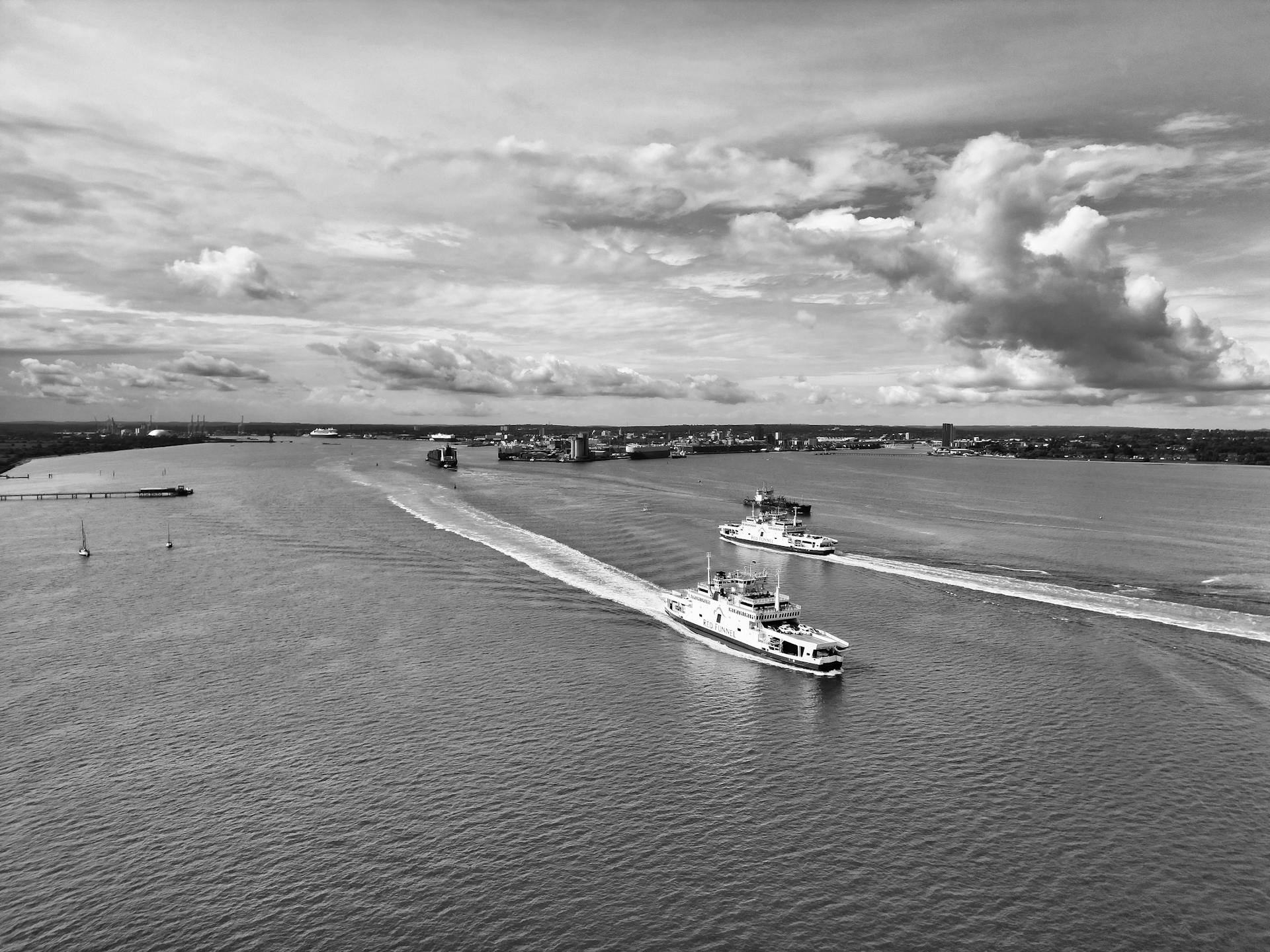 Aerial black and white capture of ferries navigating Southampton Water with dramatic sky.