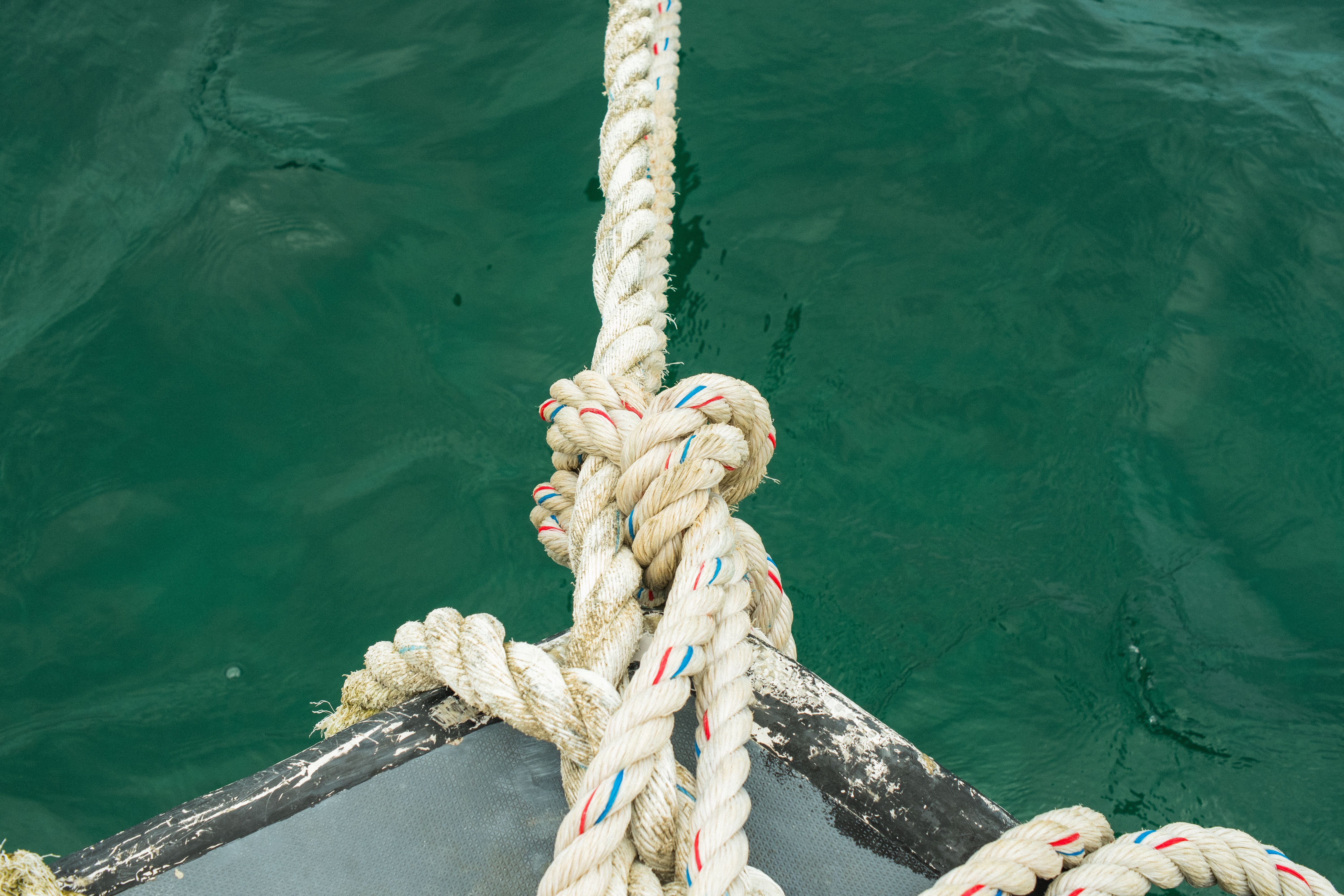 Primo piano di una cima fissata alla prua di una barca sul mare verde intenso.