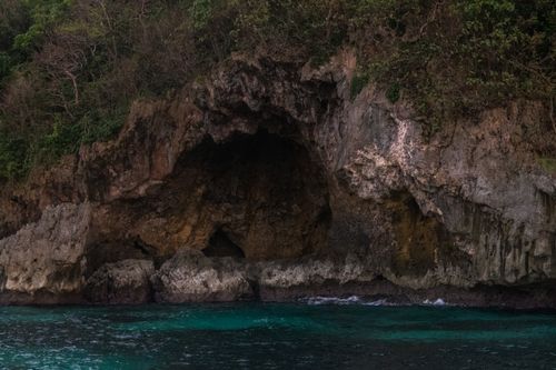 Free A breathtaking view of a rocky coast with vibrant green foliage and clear turquoise waters. Stock Photo