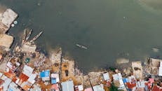 从鸟瞰视角看，平静的海岸上停泊着沿海定居点的船只，屋顶色彩鲜明