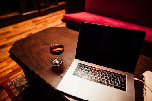 A cozy indoor setting with a laptop and beverage on a wooden table, ideal for remote work.